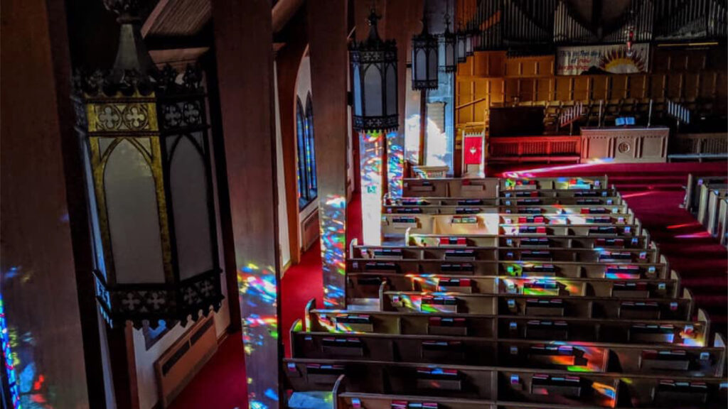 a photo of our sanctuary with the sun coming through the stained glass windows